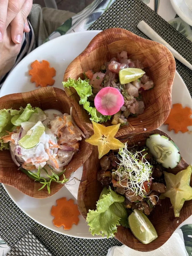 Trio de poisson cru présenté dans trois coupelles en bois, fleurs comestibles